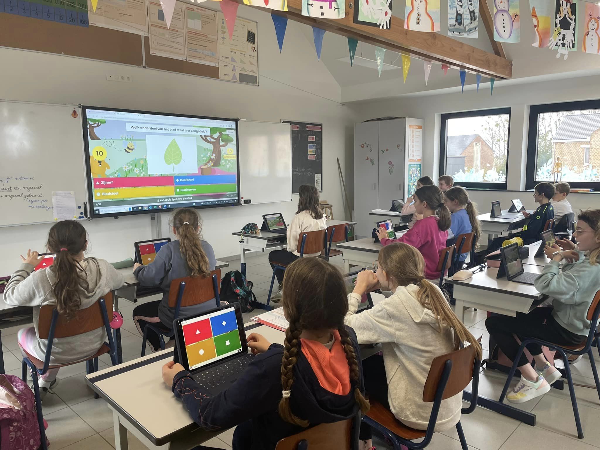 Leerlingen in het 5de leerjaar spelen een Kahoot-quiz op de iPads en het digitale bord